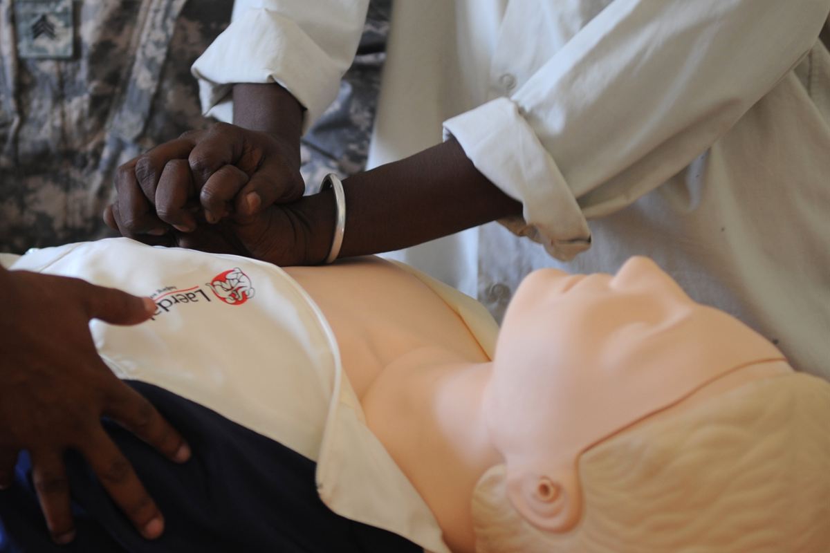 Mains d'un stagiaire pratiquant un massage cardiaque sur un mannequin de secourisme