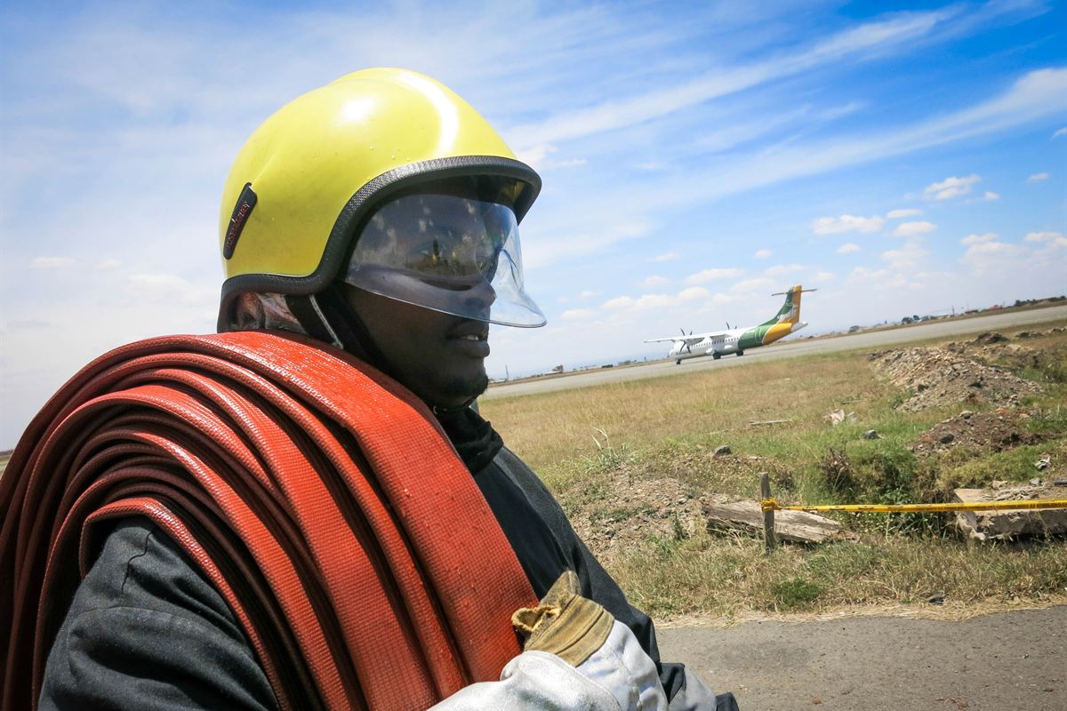 Portrait d'un sapeur-pompier casqué portant un tuyau d'incendie sur l'épaule